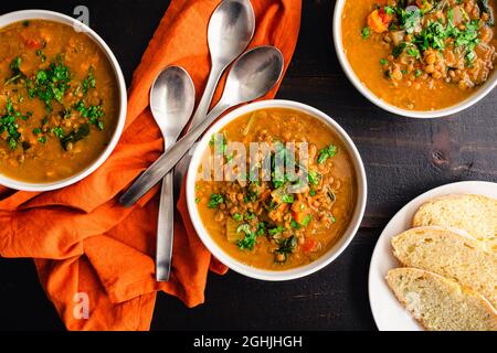 Zuppa di lenticchie di patate dolci marocchine guarnita con erbe fresche: Zuppa di verdure e lenticchie con erbe fresche servite con pane fresco Foto Stock