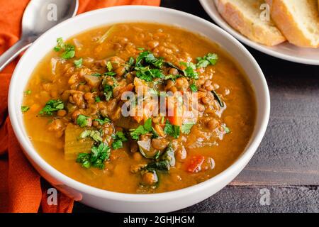 Zuppa di lenticchie di patate dolci marocchine guarnita con erbe fresche: Zuppa di verdure e lenticchie con erbe fresche servite con pane fresco Foto Stock