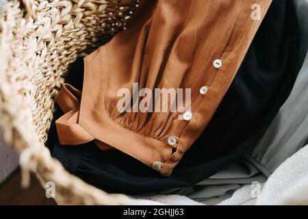 Primo piano immagine di un cestino di vimini pieno con abiti estivi per lavare laungry. Vista dall'alto. Foto Stock