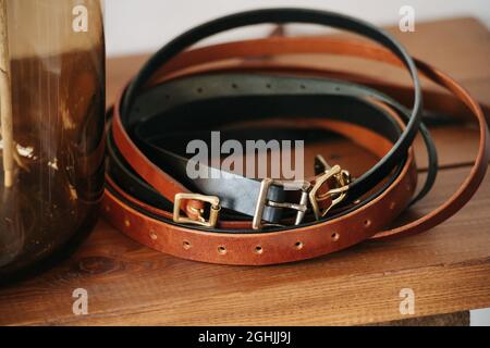 Diverse cinture in vita arrotolato in un cerchio su un ponte di tavolo. Accanto a un vaso di vetro. Foto Stock