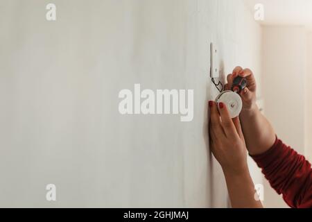 Scatto orizzontale delle mani di una donna che ripara un campanello nella sua casa con un cacciavite. Foto Stock