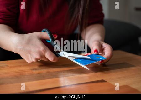 donna irriconoscibile che taglia una carta di credito a metà con le forbici Foto Stock