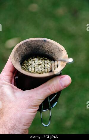 Uomo che tiene con la mano un compagno con yerba e acqua calda. Pronto a bere. Foto Stock