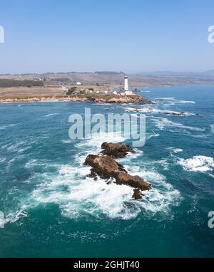 Le onde fredde dell'Oceano Pacifico si infrangono contro l'aspra e panoramica costa settentrionale della California, dove un faro si trova a nord di Santa Cruz. Foto Stock