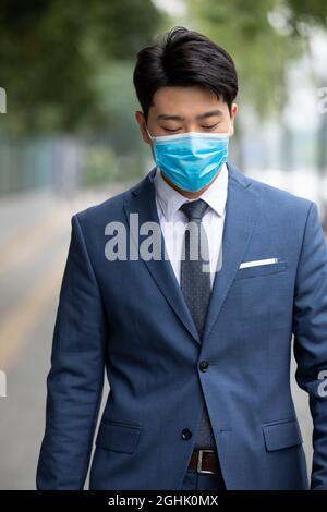 Uomo d'affari che indossa maschera chirurgica per andare al lavoro Foto Stock