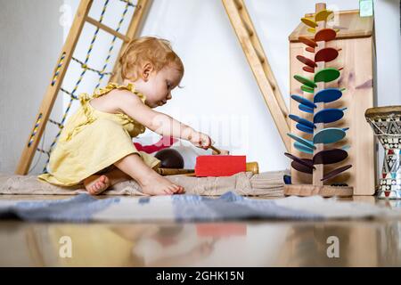 Cute bambino ragazza che gioca legno xylophone ecologia giocattoli Maria Montessori materiali Foto Stock