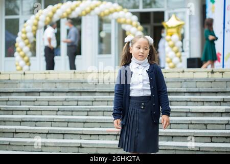 Bella ragazza in maschera andando a 1 grado a scuola Foto Stock