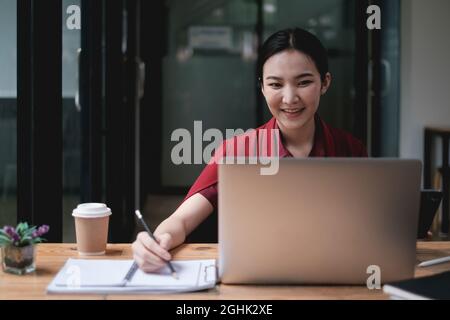 Giovane università femminile prendendo appunti e utilizzando l'evidenziatore. Studente focalizzato in aula online. Concetto di istruzione autentica Foto Stock