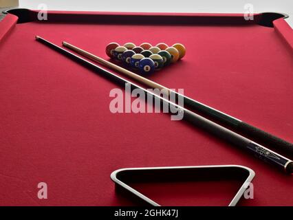 Palline da biliardo sul tavolo da biliardo in feltro rosso con spunti e rack nero Foto Stock