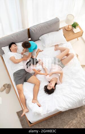 Felice giovane famiglia che si diverte a letto Foto Stock