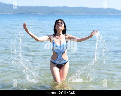 Donna russa di 45 anni in costume da bagno che ride e sta in piedi nel mare giapponese Foto Stock