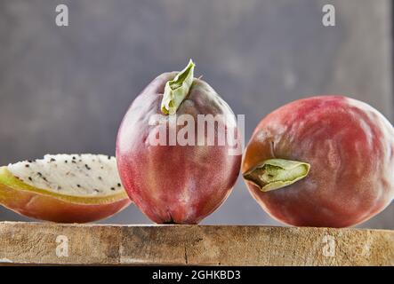 Frutta di cactus di mela peruviana intera e tagliata su supporto di legno su tavola grigia. Nome scientifico Cereus repandus. Foto Stock