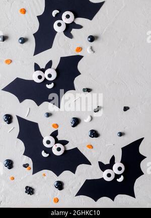 Dietro l'altro Halloween. Pipistrelli decorativi divertenti. Dolciumi cosparsi su sfondo beige, copia del testo, messa a fuoco selettiva Foto Stock