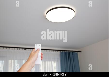 Moderno lampadario a soffitto a LED con pannello di controllo spento. Regolazione della luminosità dell'illuminazione nella stanza Foto Stock