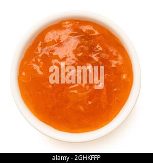 Confettura di albicocche in una ciotola bianca di ceramica isolata su bianco. Vista dall'alto. Foto Stock