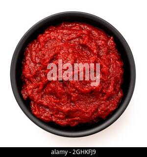 Concentrato di pomodoro in una ciotola di ceramica nera isolata su bianco. Vista dall'alto. Foto Stock