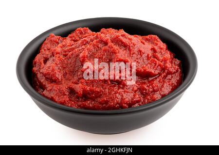 Concentrato di pomodoro in una ciotola di ceramica nera isolata su bianco. Foto Stock