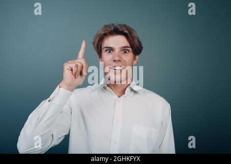 Giovane uomo che punta e indice dell'indice dell'indice dell'indice verso l'alto Foto Stock