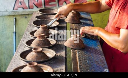 Venditore di sorabi o surabi o serabi, pancake tradizionale indonesiano, cucinato con ceramica o padella tradizionale con legna da ardere. Foto Stock