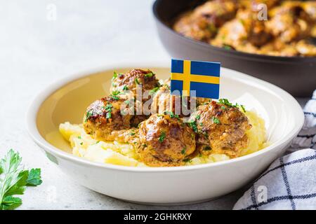 Polpette svedesi in salsa cremosa con purè di patate in un piatto bianco, sfondo grigio. Concetto di cibo scandinavo. Foto Stock