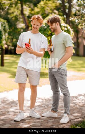 Due ragazzi con bottiglie in piedi che parlano nel parco Foto Stock