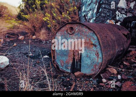 Bidón de metal deteriorado, en balsa de alquitrán y terreno contaminado Foto Stock