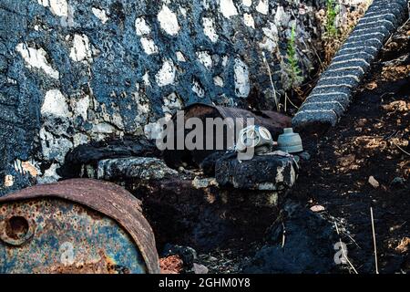 Bidón de metal deteriorado, en balsa de alquitrán y terreno contaminado Foto Stock