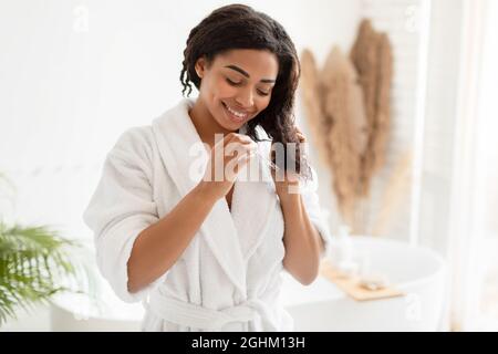 Trattamento a Parti Separate. Donna Nera Sorridente Che Spruzza Olio  Essenziale Sui Capelli Ricci Fotografia Stock - Immagine di richiedere,  cura: 183507818