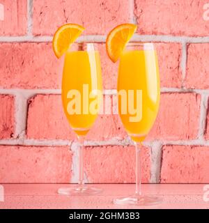 Rinfrescanti cocktail Mimosa all'arancia con champagne su sfondo luminoso. Foto Stock