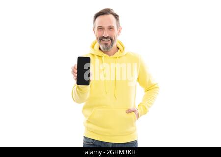 felice uomo maturo in hoody che presenta lo spazio di copia schermo dello smartphone isolato su bianco, promozione. Foto Stock