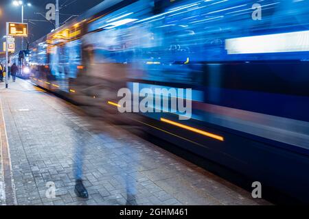 il tram lascia la fermata nella città di notte, vista di movimento sfocato Foto Stock