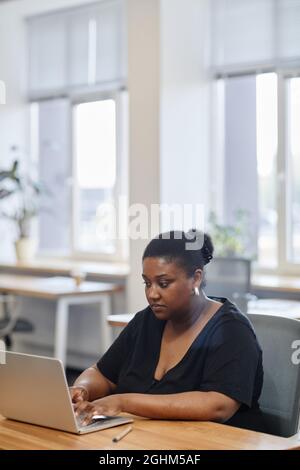 Ritratto di seria imprenditore femminile che lavora su laptop alla scrivania in un ufficio moderno, riempire i moduli online Foto Stock