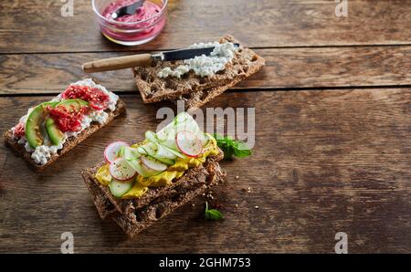 Da sopra di vari deliziosi toast di croccante con verdure servite su un tavolo di legno per uno spuntino vegetariano Foto Stock