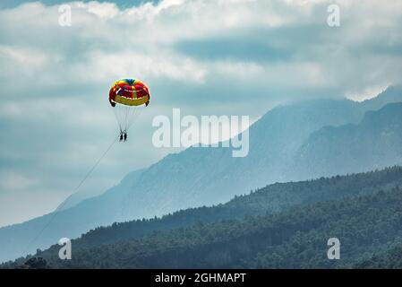 silhouette di coppia felice parasailing sul mare tropicale. Estate azioni estreme Foto Stock