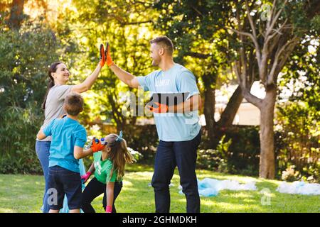 I genitori caucasici, figlio e figlia che pescavano in alto, ripulendo i rifiuti nelle campagne Foto Stock