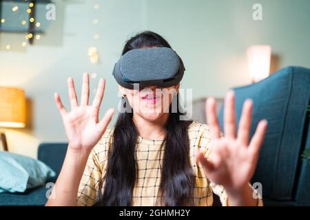 Gioiosa emozionata giovane ragazza che ha sperimentato la realtà virtuale a 360 gradi o occhiali di protezione per realtà virtuale o cuffie a casa - concetto di utilizzare la tecnologia moderna e. Foto Stock