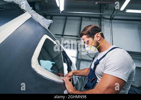 Muscoloso riparatore che mette il nastro del condotto su finestre auto Foto Stock