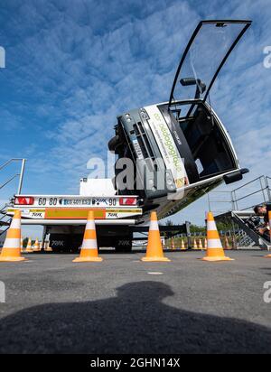 07 settembre 2021, Renania Settentrionale-Vestfalia, Münster: Nella messa a punto del test sul sito di crash test, un piccolo pullman occupato dai passeggeri si inclina di 90 gradi sul suo lato utilizzando l'impianto idraulico. Questa prova riguarda la questione se e come i passeggeri possono lasciare il veicolo in caso di incendio, ad esempio nel caso di un autobus capovolto. Sul posto è disponibile una cabina per autobus come veicolo di prova che può essere inclinato a diverse angolazioni. Foto: Guido Kirchner/dpa Foto Stock