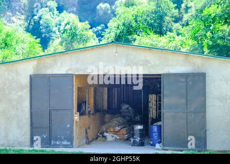 Immagine frontale di una stalla o fienile in montagna. All'interno è visibile un cavallo. Foto Stock