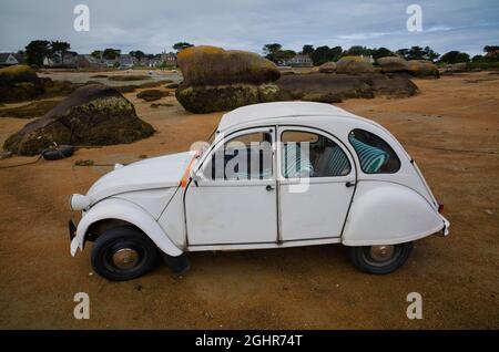 Citroen 2CV Ente, sulla spiaggia di Ile Renote, costa rocciosa lungo il Sentier des douaniers, Tregastel, Cote de Granit Rose, Cotes d'Armor Foto Stock