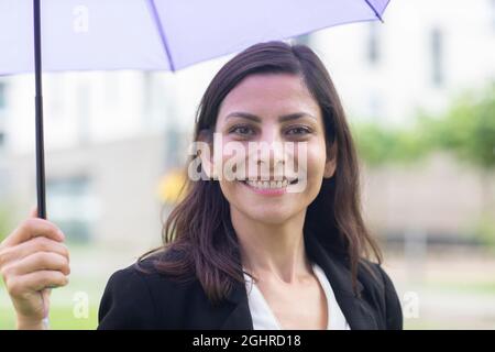 Direttore serio di mezza età fuori con ombrello in mano, Friburgo, Baden-Wuerttemberg, Germania Foto Stock