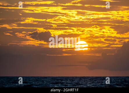 Cielo giallo arancio con nuvole e sole vicino al tramonto sul Golfo del Messico nella Florida sud-occidentale degli Stati Uniti Foto Stock