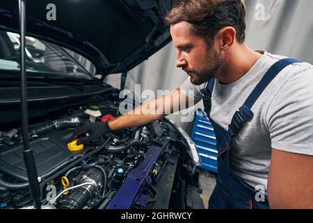 Il personale di riparazione apre un tappo per il controllo dell'olio motore Foto Stock