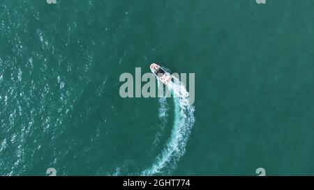 Motoscafo a vela nel mare turchese. Vista aerea. Barca a vela veloce nel mare calmo facendo onde schiumose. Vista dall'alto durante il giorno a Benidorm, Spagna. Concetto di vacanza e di viaggio. Foto Stock