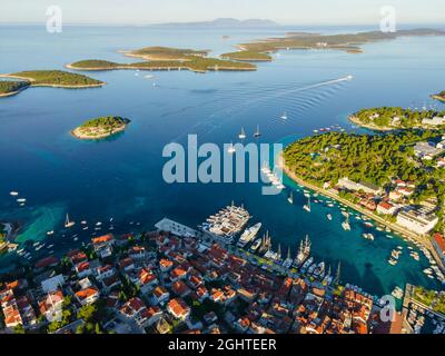 Vista aerea della città vecchia di Hvar con baia d'acqua turchese con yacht e isole in Croazia e mare Adriatico fatto con drone. Vacanze estive Foto Stock