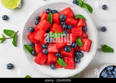 Insalata estiva di cocomeri e mirtilli con succo di lime e menta su un tavolo di marmo bianco. Vista dall'alto. Cibo sano Foto Stock