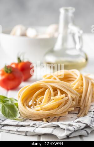 Nido di pasta italiana. Gli spaghetti non cotti nidificano sul tavolo bianco. Foto Stock