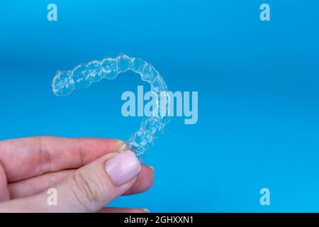 Regge a mano allineatori trasparenti invisibili rimovibili invisalign o plastici reggiseni ortodontici su sfondo blu Foto Stock