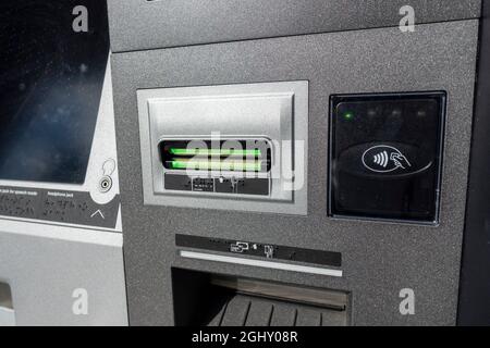 Vista ravvicinata dello slot di inserimento di una scheda ATM e tocca per eseguire la scansione di un quadrato all'esterno di un edificio bancario. Foto Stock