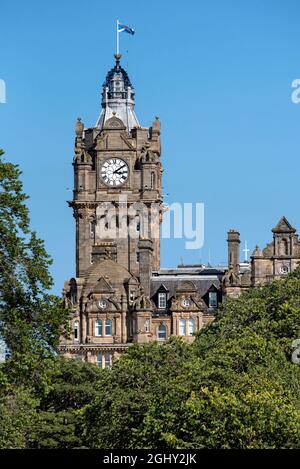 La torre di orologio del Balmoral Hotel visto attraverso gli alberi in Princes Street Gardens, Edimburgo, Scozia, Regno Unito. Foto Stock